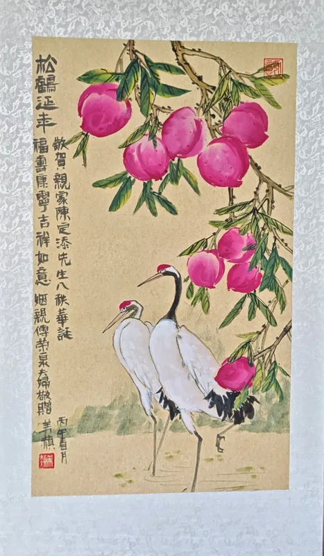 Ink painting on a hanging scroll: two red-crowned cranes under a branch heavy with pink peaches