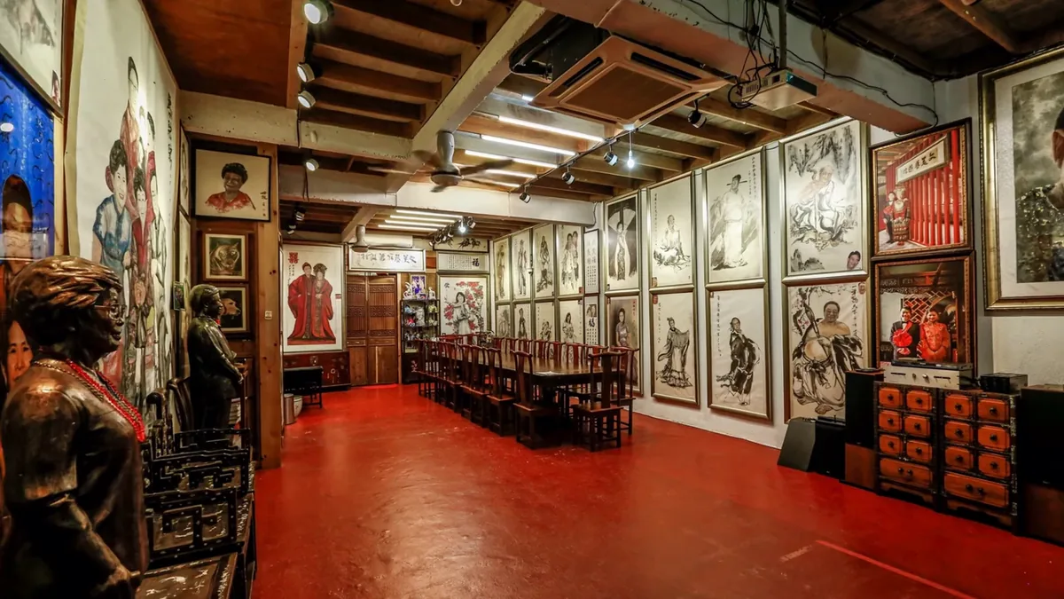 Inside the gallery: framed paintings along the walls, a red carpet, old rosewood furniture