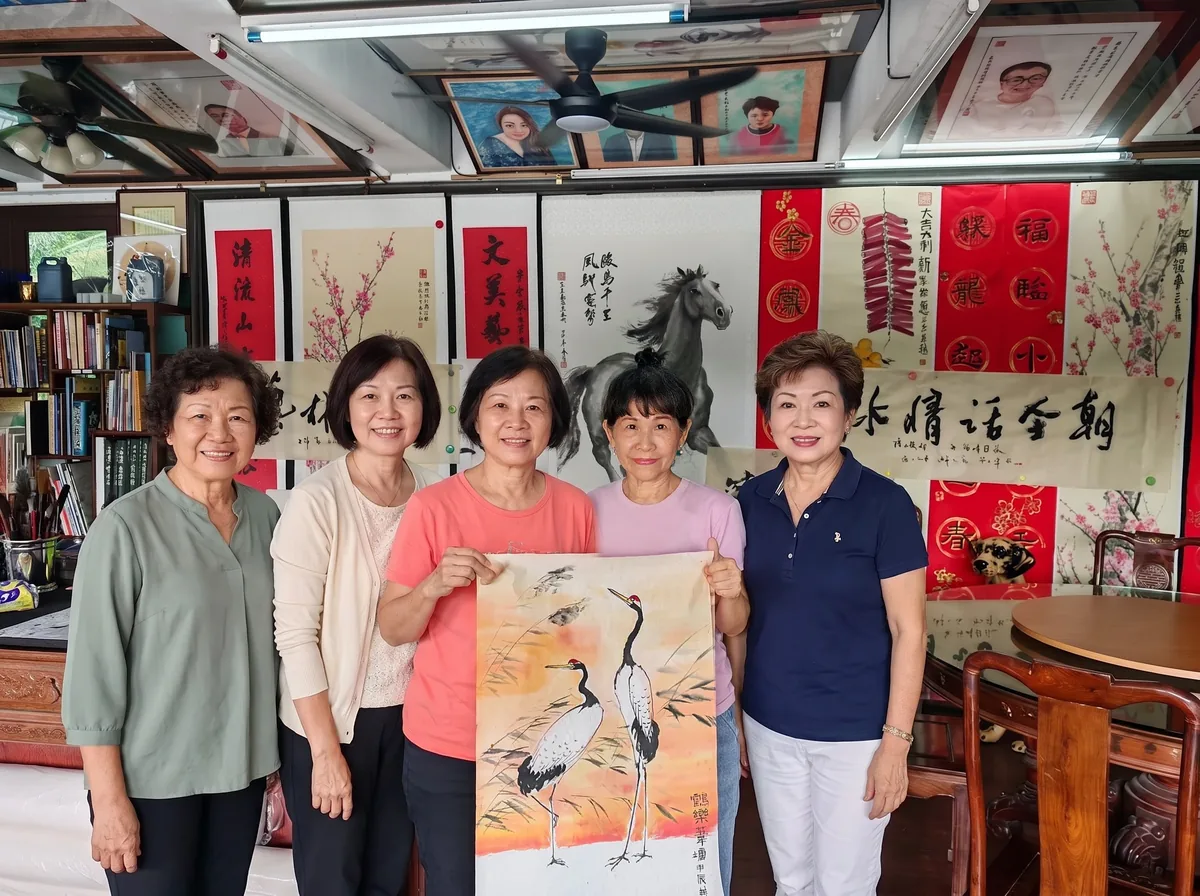 Five guests holding up a painting of cranes in the gallery